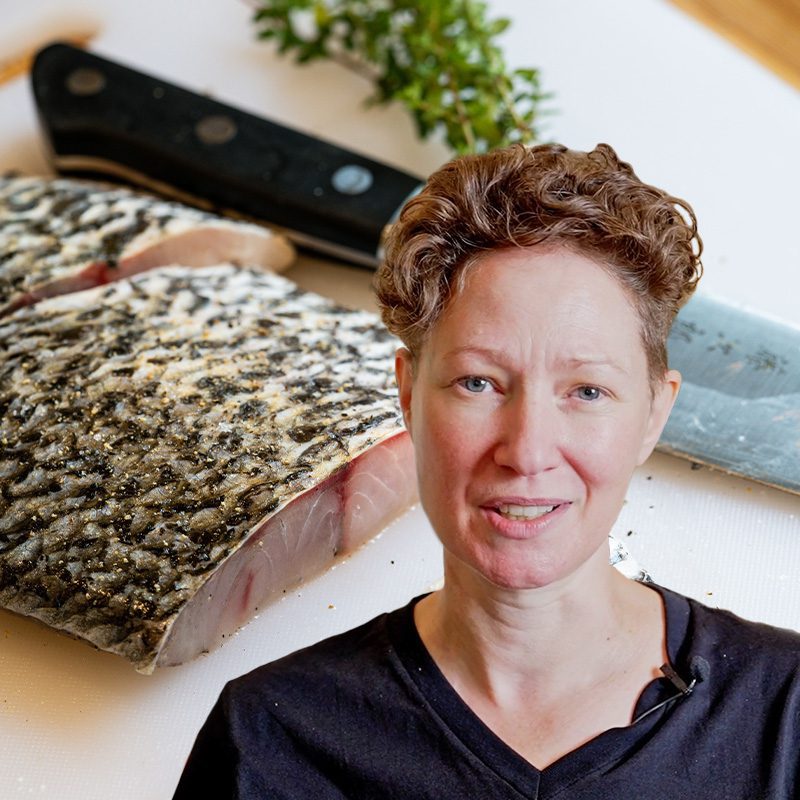 Chef Fiona Lewis standing next to a fish and knife on a table